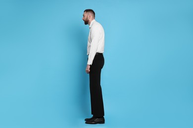 Man with poor posture on light blue background