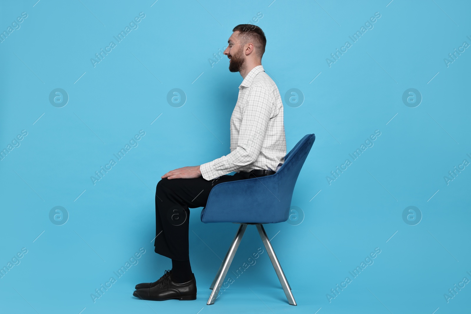 Photo of Man with good posture sitting on chair against light blue background