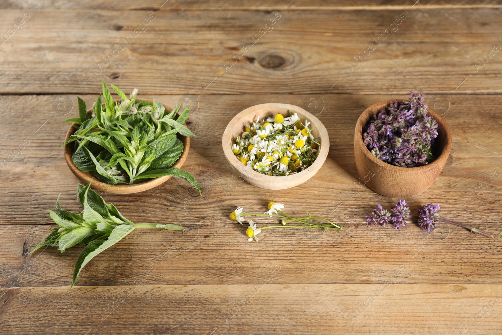 Photo of Different healing herbs in bowls on wooden table