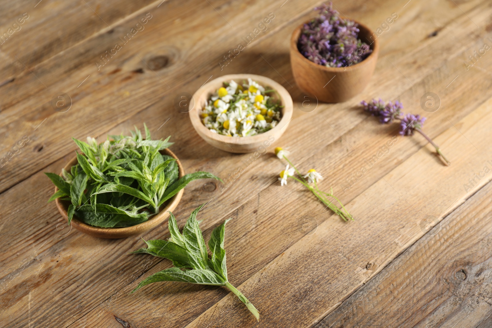 Photo of Different healing herbs in bowls on wooden table