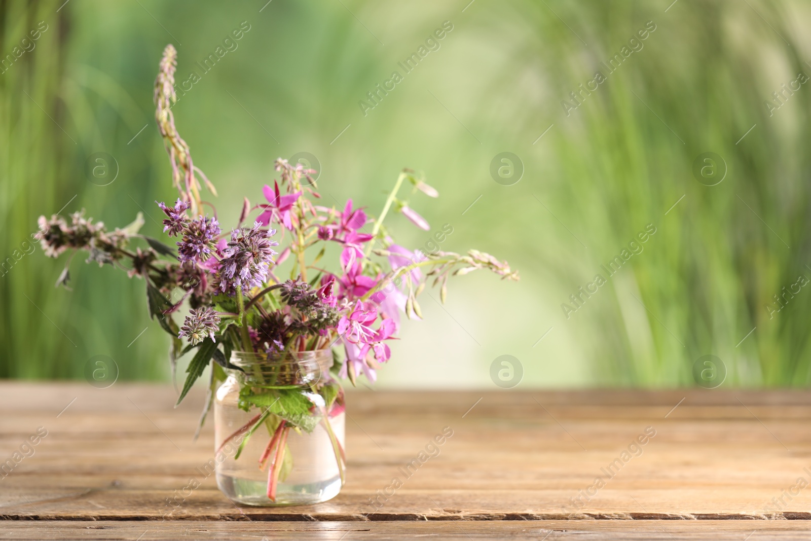 Photo of Bouquet of different healing herbs on wooden table. Space for text