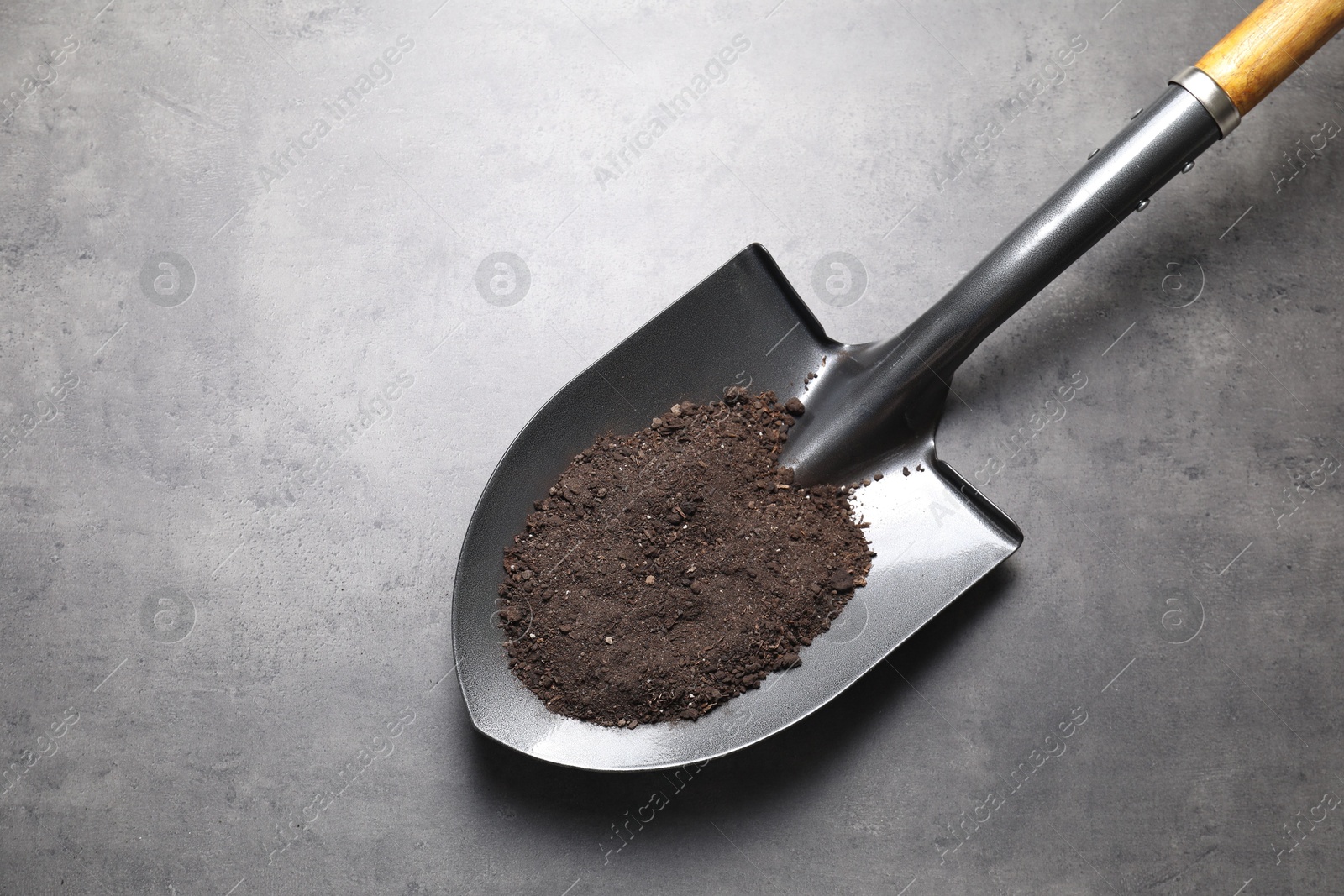 Photo of Metal shovel with soil on grey table, top view. Space for text