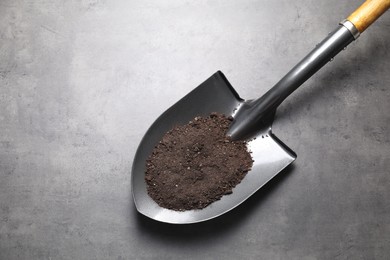 Photo of Metal shovel with soil on grey table, top view. Space for text