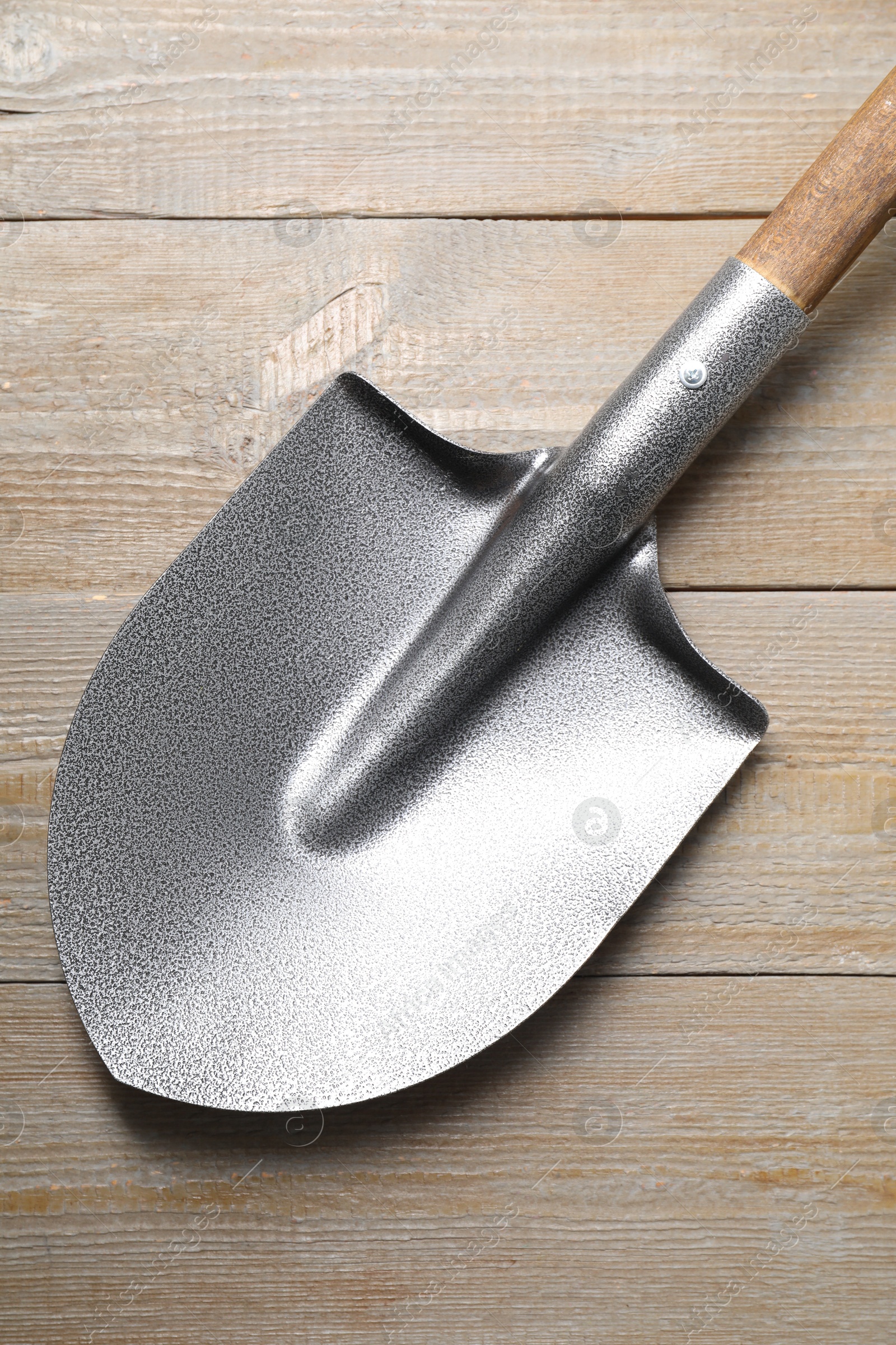 Photo of Metal shovel on light wooden table, top view