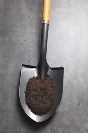 Photo of Metal shovel with soil on grey table, top view