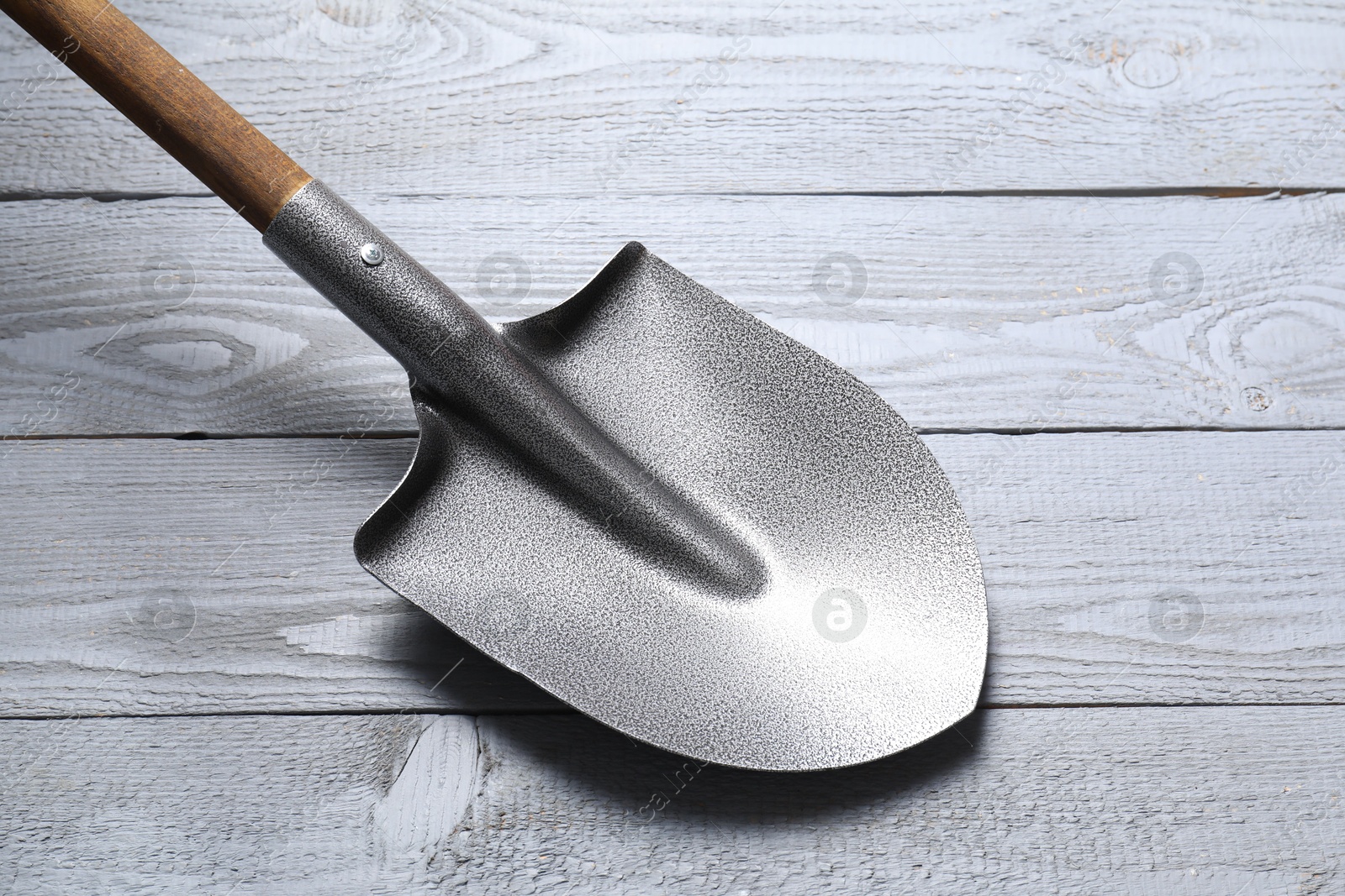 Photo of Metal shovel on light grey wooden table