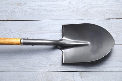 Photo of Metal shovel on light grey wooden table, top view