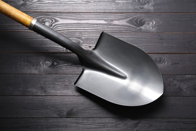 Photo of Metal shovel on black wooden table, top view