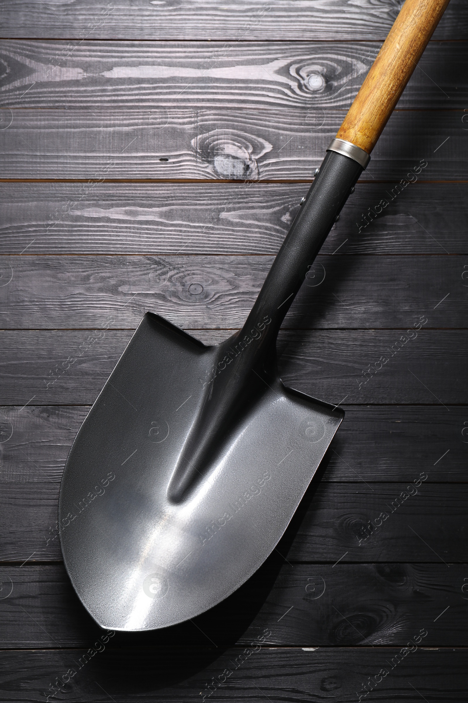 Photo of Metal shovel on black wooden table, top view