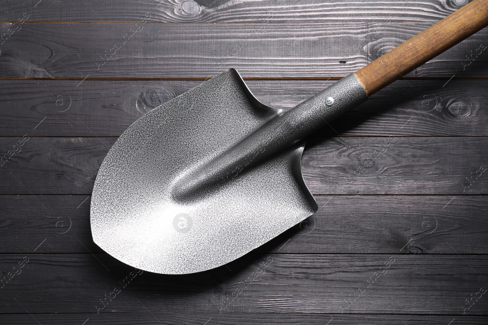 Photo of Metal shovel on black wooden table, top view