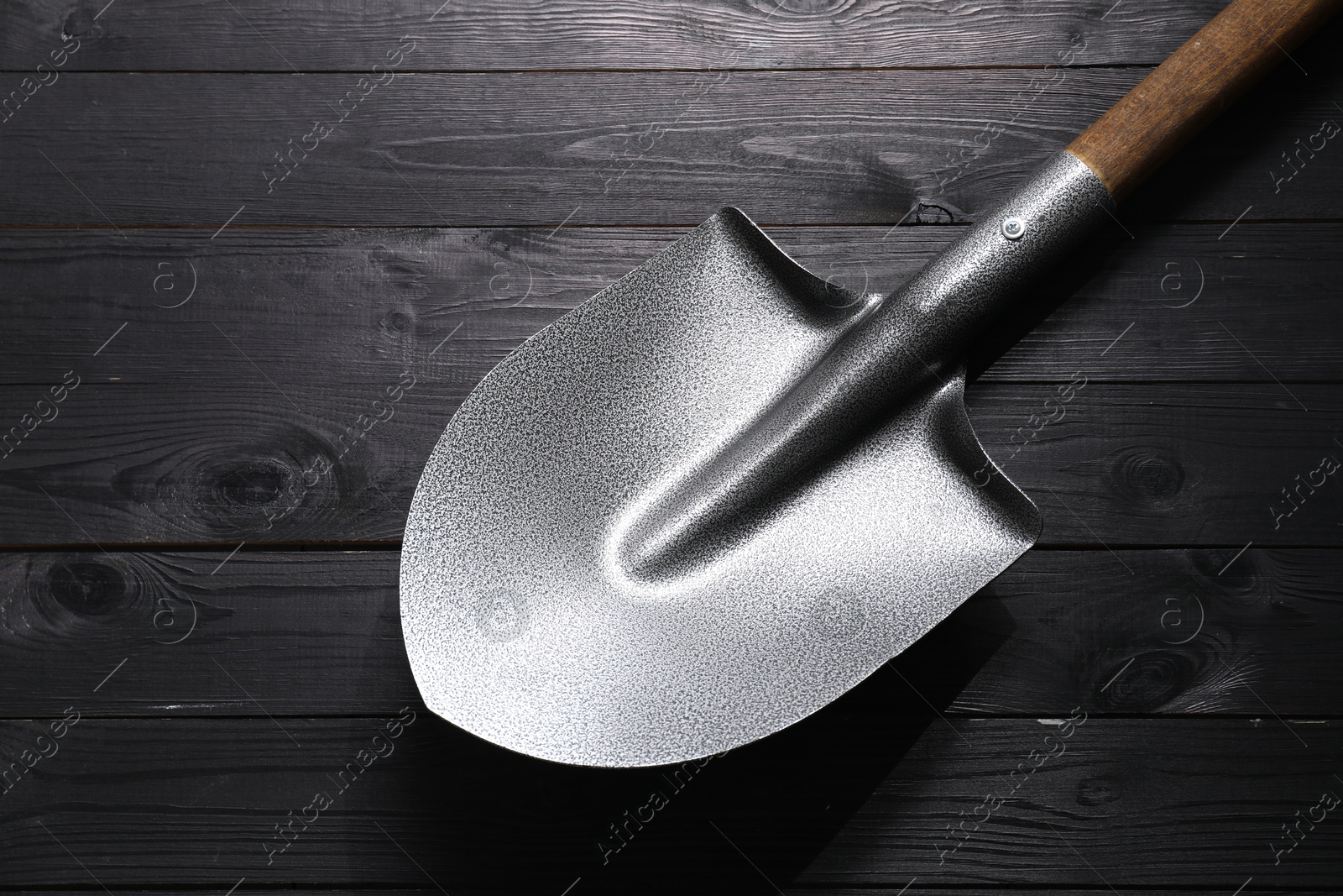 Photo of Metal shovel on black wooden table, top view