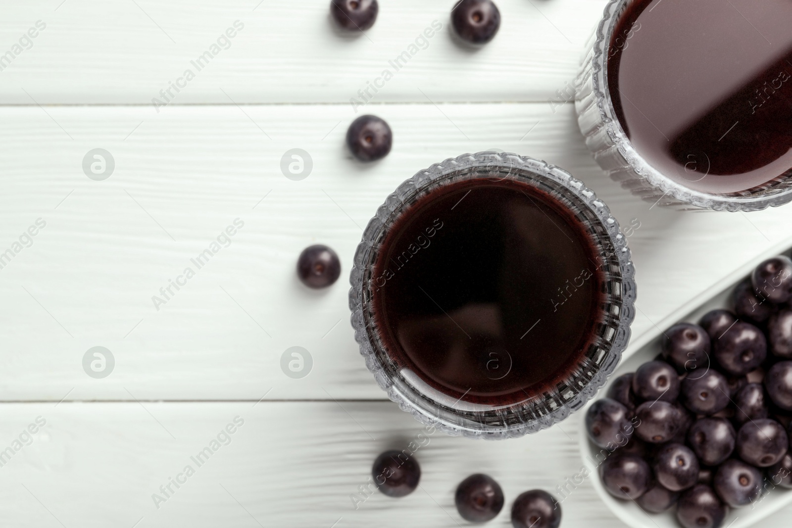 Photo of Delicious acai juice in glasses and berries on white wooden table, flat lay. Space for text