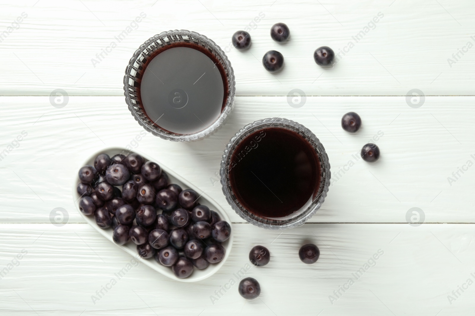 Photo of Delicious acai juice in glasses and berries on white wooden table, flat lay