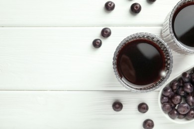 Delicious acai juice in glasses and berries on white wooden table, flat lay. Space for text