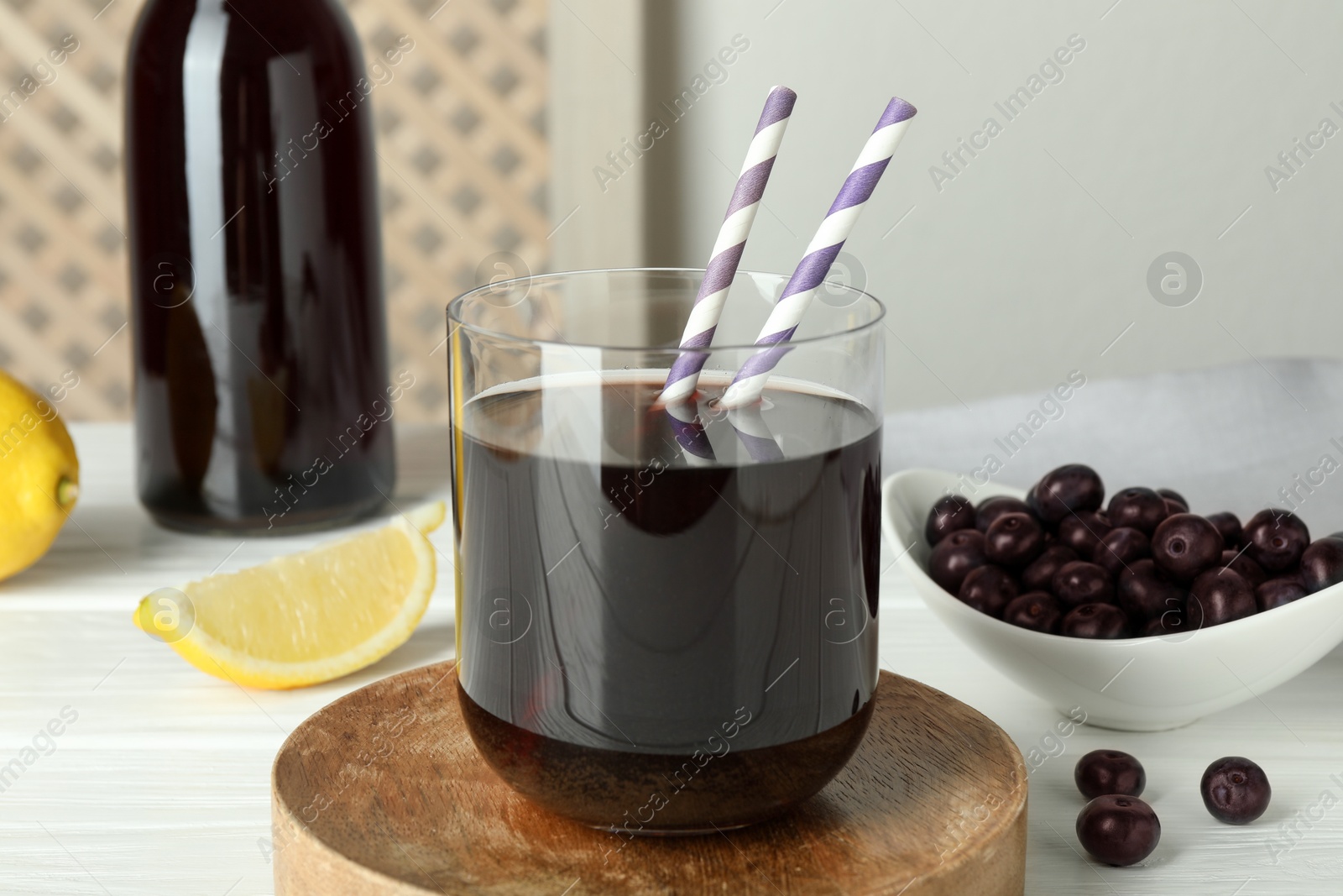 Photo of Delicious acai juice, berries and lemon on white wooden table