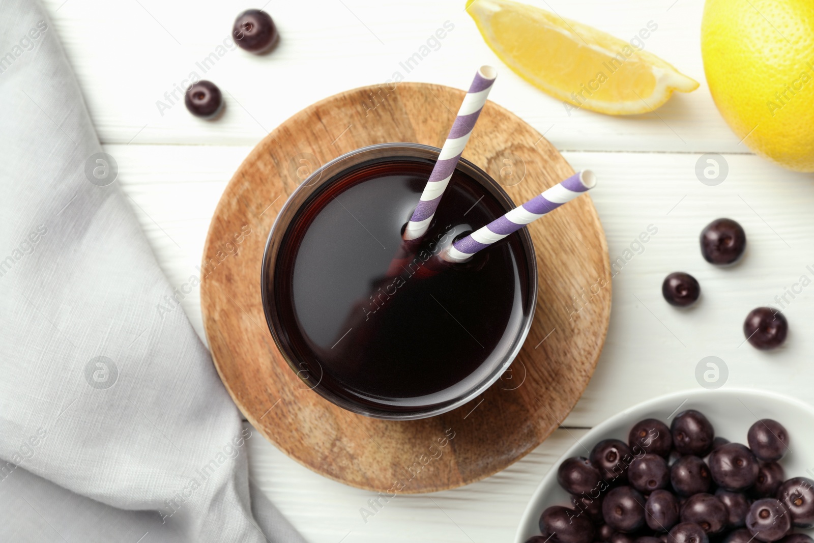 Photo of Delicious acai juice in glass, berries and lemon on white wooden table, flat lay