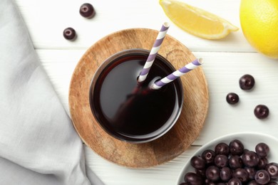 Delicious acai juice in glass, berries and lemon on white wooden table, flat lay