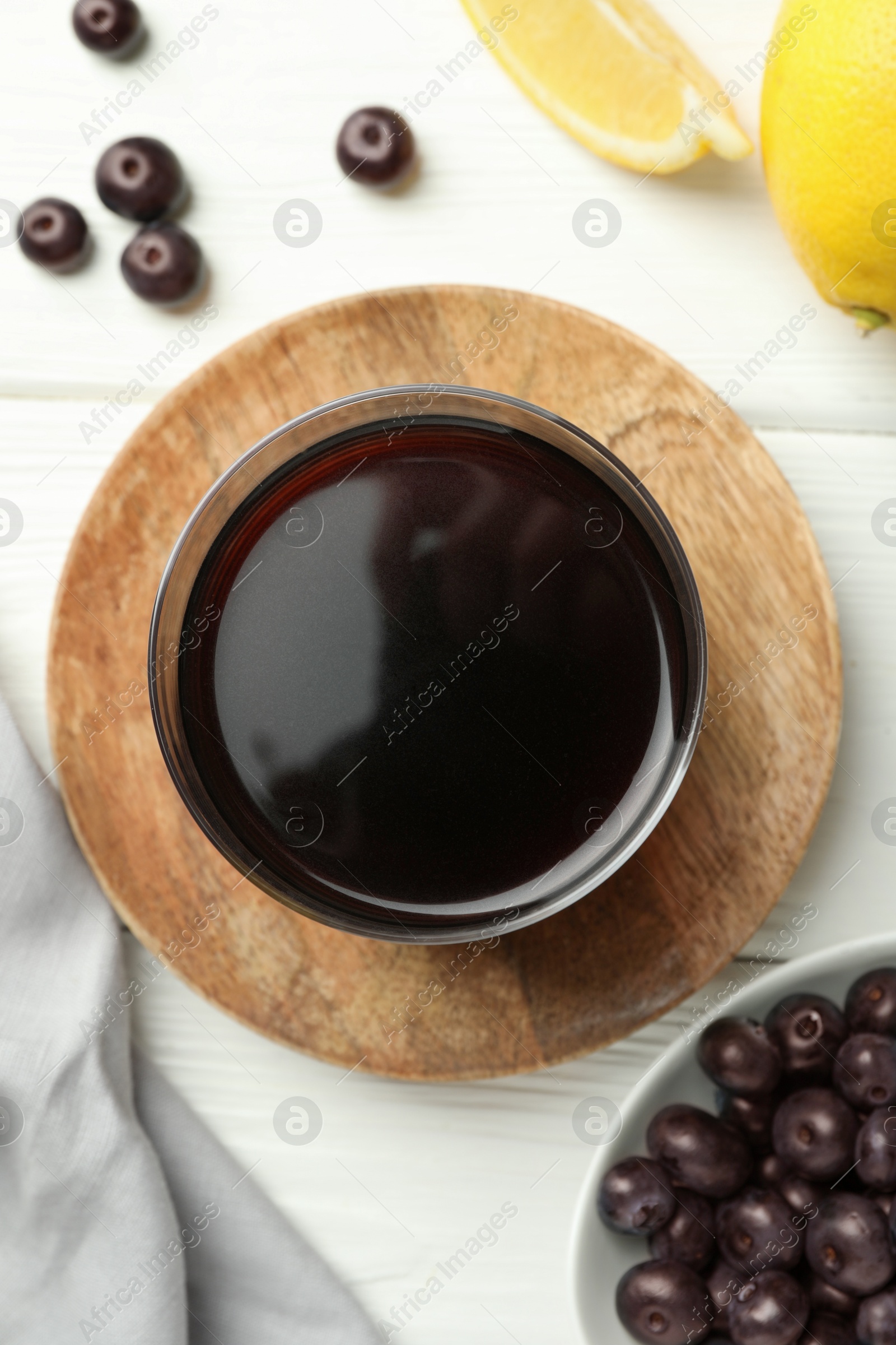 Photo of Delicious acai juice in glass, berries and lemon on white wooden table, flat lay