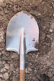 Photo of Metal shovel on soil outdoors, top view