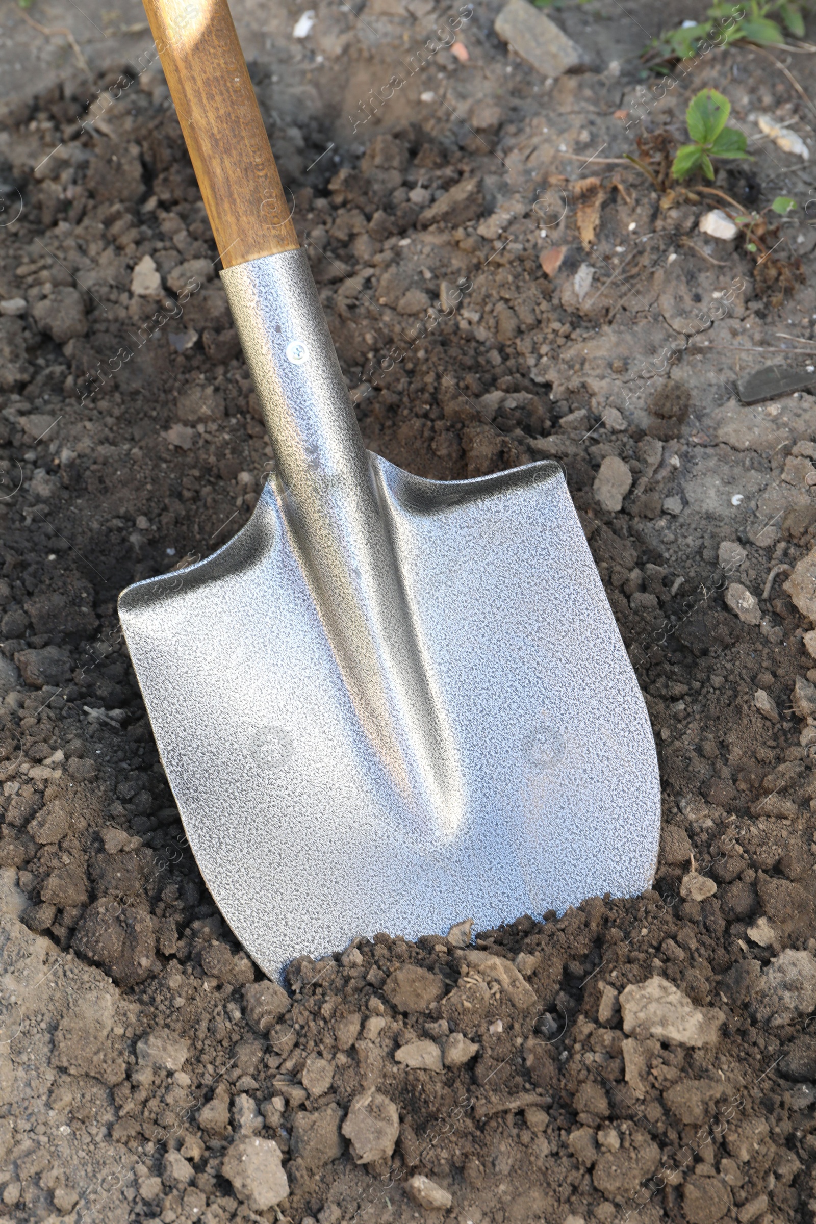 Photo of Digging soil with shovel in garden, closeup