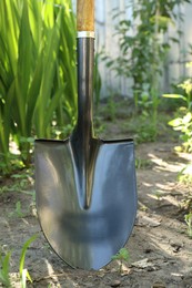 Photo of Metal shovel stuck in soil. Gardening tool