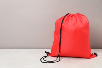 Photo of Red drawstring bag on light marble table. Space for text