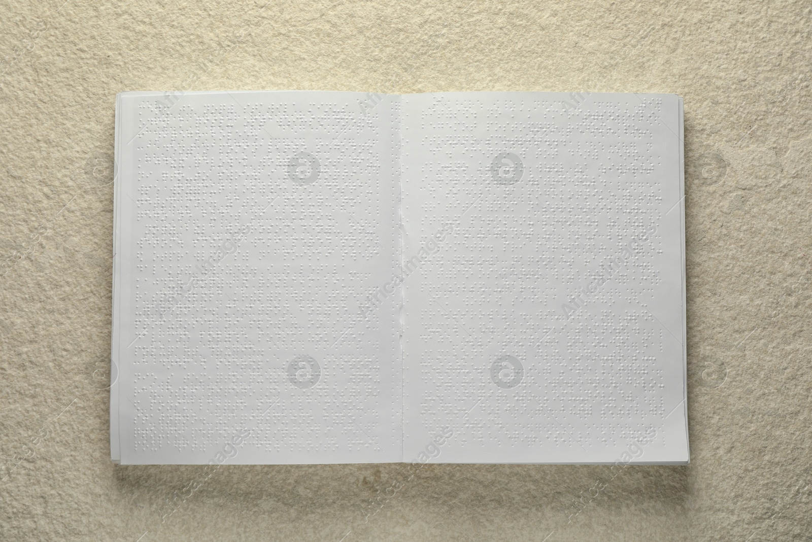 Photo of Book with Braille text on beige textured table, top view. Education and leisure for blind people