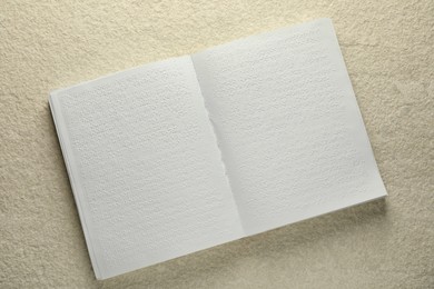 Book with Braille text on beige textured table, top view. Education and leisure for blind people