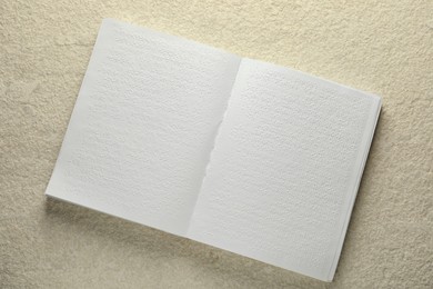 Photo of Book with Braille text on beige textured table, top view. Education and leisure for blind people