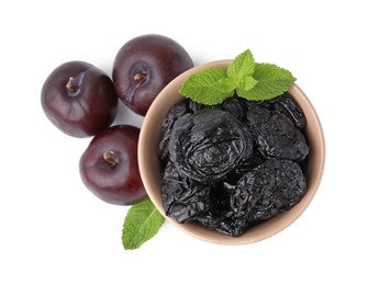 Delicious prunes in bowl, fresh ripe plums and mint isolated on white, top view