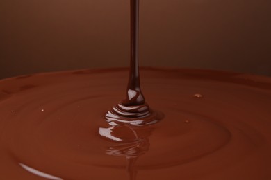 Photo of Pouring delicious melted chocolate on brown background, closeup