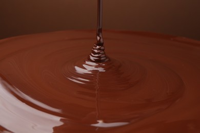 Photo of Pouring delicious melted chocolate on brown background, closeup