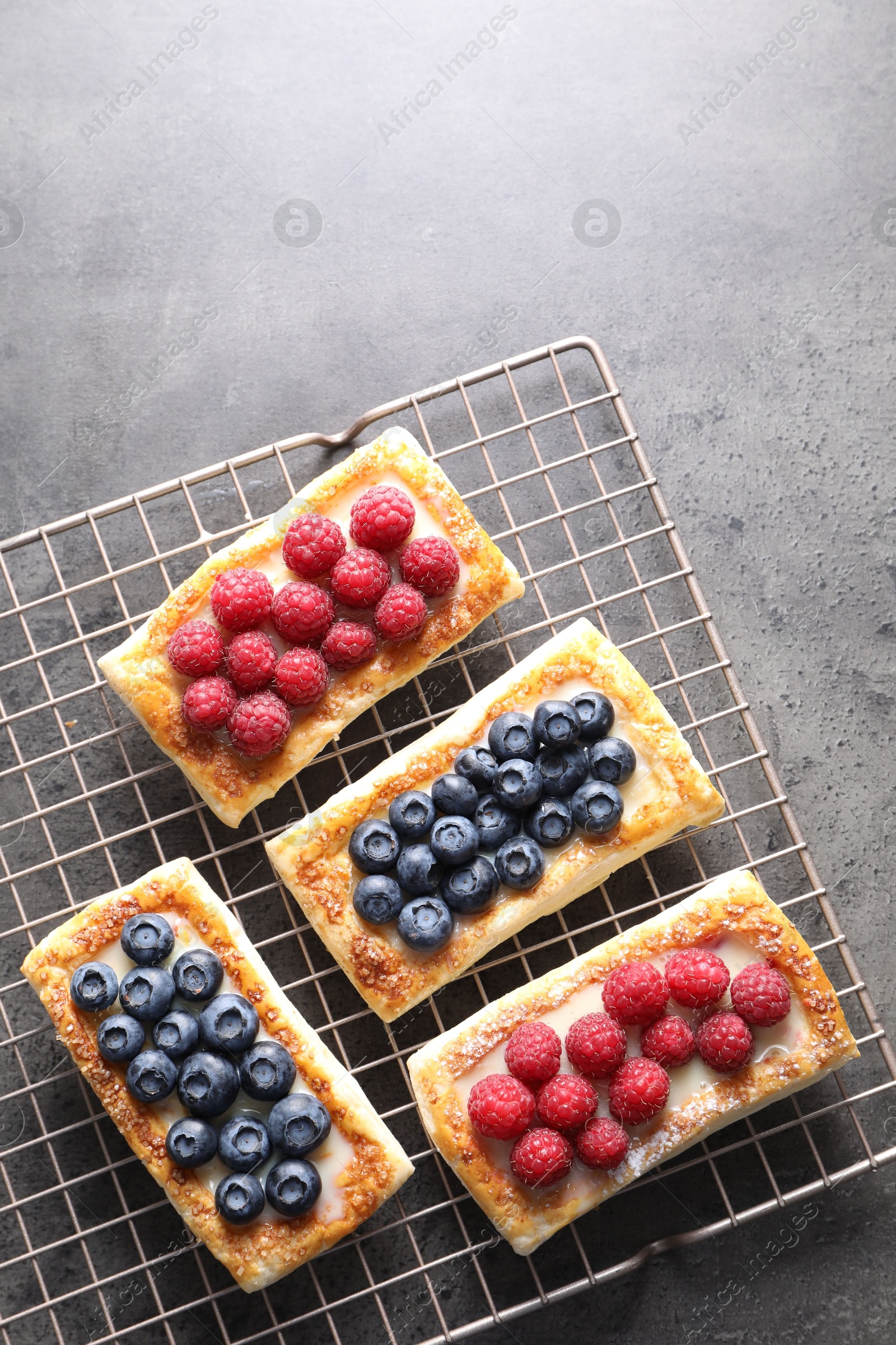 Photo of Tasty puff pastries with berries on grey table, top view