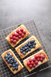 Tasty puff pastries with berries on grey table, top view