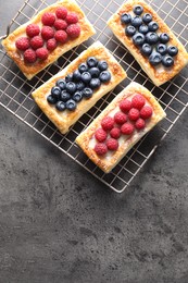 Photo of Tasty puff pastries with berries on grey table, top view. Space for text