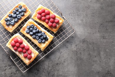 Tasty puff pastries with berries on grey table, top view. Space for text