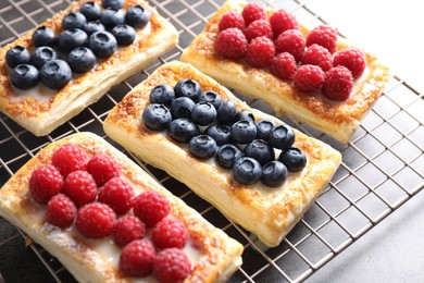 Photo of Tasty puff pastries with berries on grey table, closeup