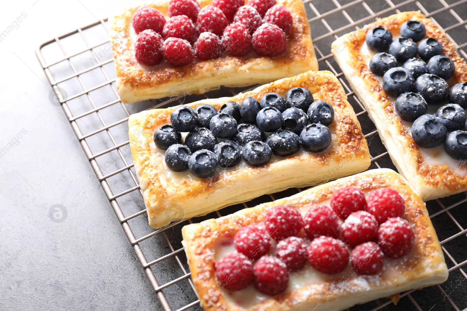 Photo of Tasty puff pastries with berries on grey table, closeup