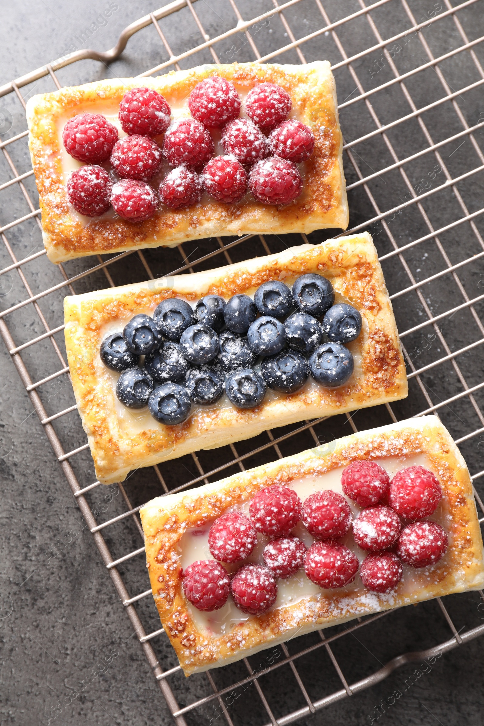 Photo of Tasty puff pastries with berries on grey table, top view