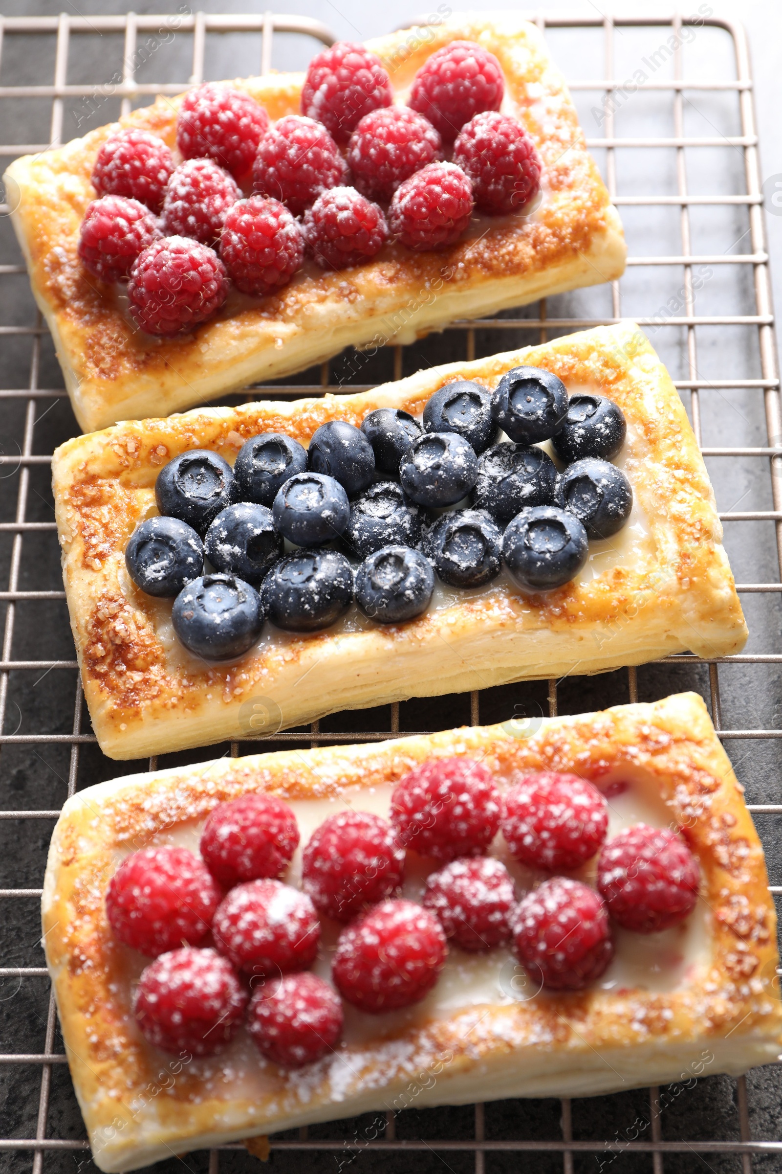 Photo of Tasty puff pastries with berries on grey table, closeup