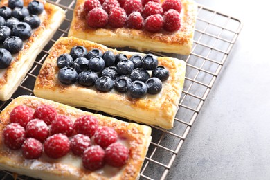 Photo of Tasty puff pastries with berries on grey table, closeup