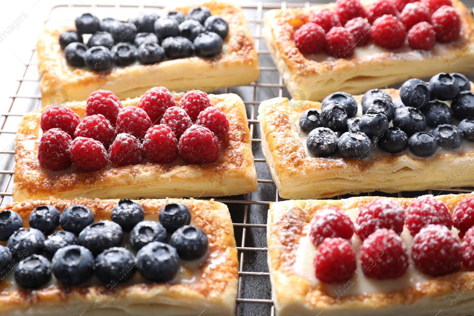 Photo of Tasty puff pastries with berries on grey table, closeup