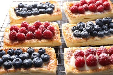 Tasty puff pastries with berries on grey table, closeup