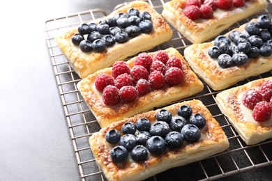 Photo of Tasty puff pastries with berries on grey table, closeup