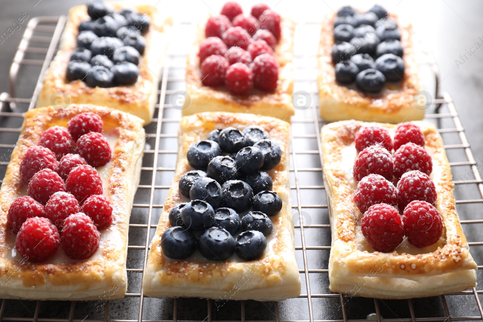 Photo of Tasty puff pastries with berries on grey table, closeup