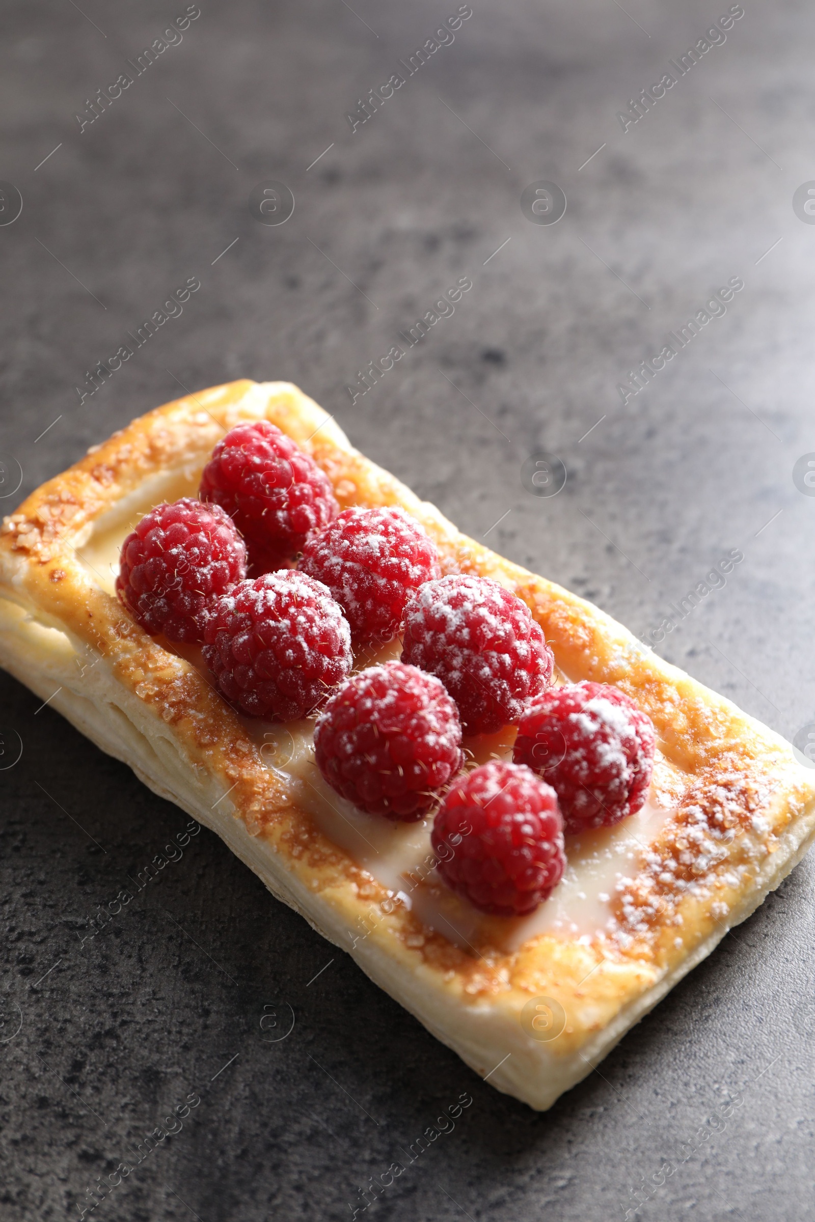 Photo of Tasty puff pastry with raspberries on grey table, closeup