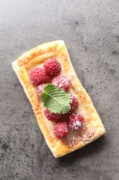 Photo of Tasty puff pastry with raspberries and mint on grey table, top view