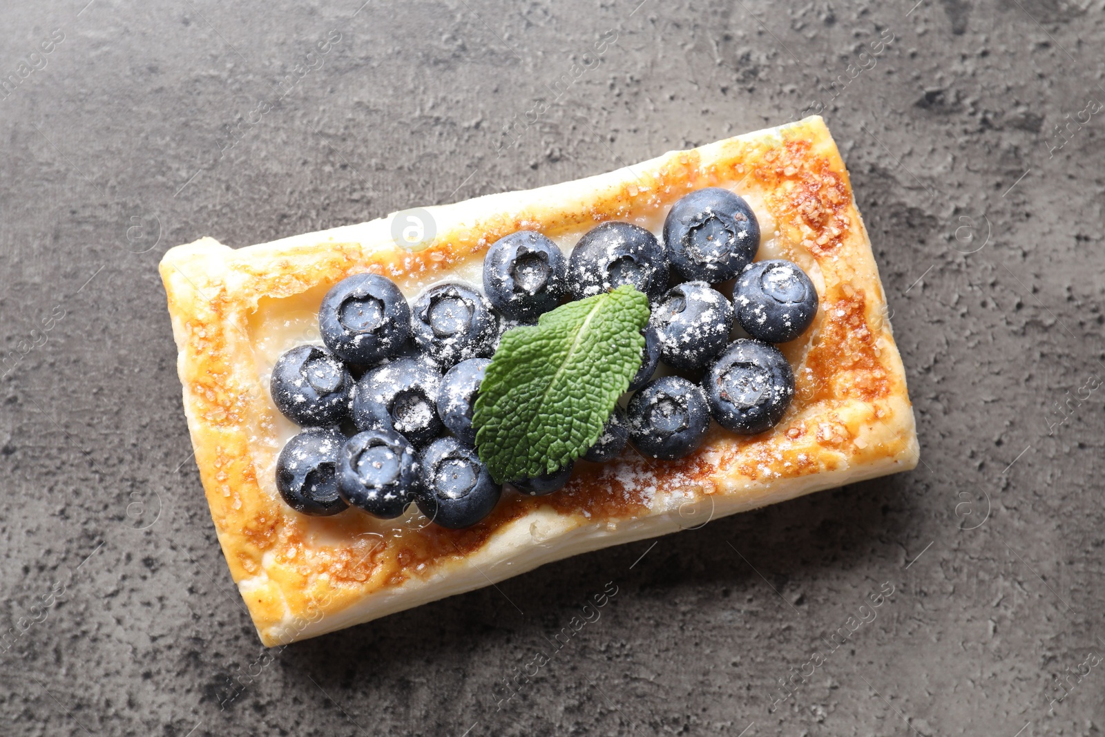 Photo of Tasty puff pastry with blueberries and mint on grey table, top view