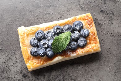 Tasty puff pastry with blueberries and mint on grey table, top view