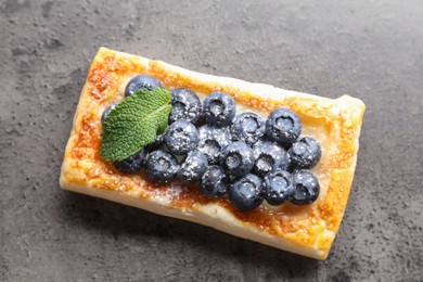 Photo of Tasty puff pastry with blueberries and mint on grey table, top view